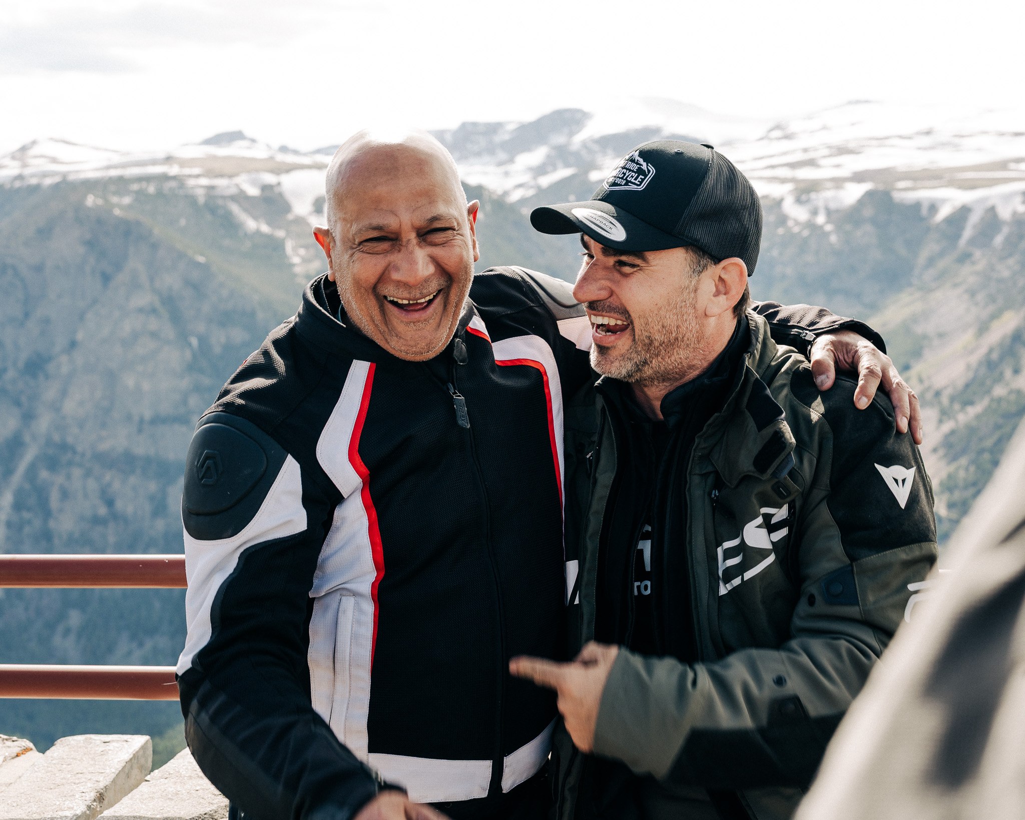 Two riders laughing together on a mountain overlook